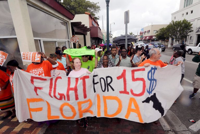 People march as they protest for increased minimum wages near a McDonald's restaurant on Thursday, Dec. 4, 2014, in the Little Havana area in Miami. Activists, fast-food workers and others are calling for increasing the minimum wage to $15 per hour and allowing workers to form unions without corporate opposition, as part of nationwide demonstrations. (AP Photo/Alan Diaz)