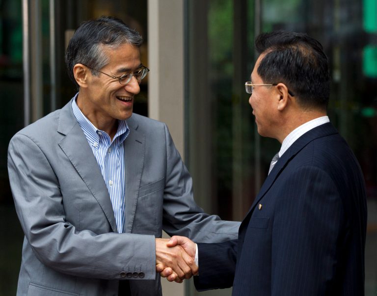FILE - In this Aug. 10, 2012 file photo, Osamu Tasaka, left, director general of the International Department at the Japanese Red Cross, and Ri Ho Rim, secretary general of North Korea's Red Cross Society, shake hands outside a hotel where they had a meeting in Beijing. Japanese and North Korean Red Cross officials will meet in China on Monday, March 3, 2014 in what could be a first step toward resuming talks between the two nations. The two sides will discuss the repatriation of remains of Japanese buried in North Korea and left behind after World War II, the Japanese Foreign Ministry said in a statement. Japan colonized Korea from 1910 to 1945. (AP Photo/Alexander F. Yuan, File)