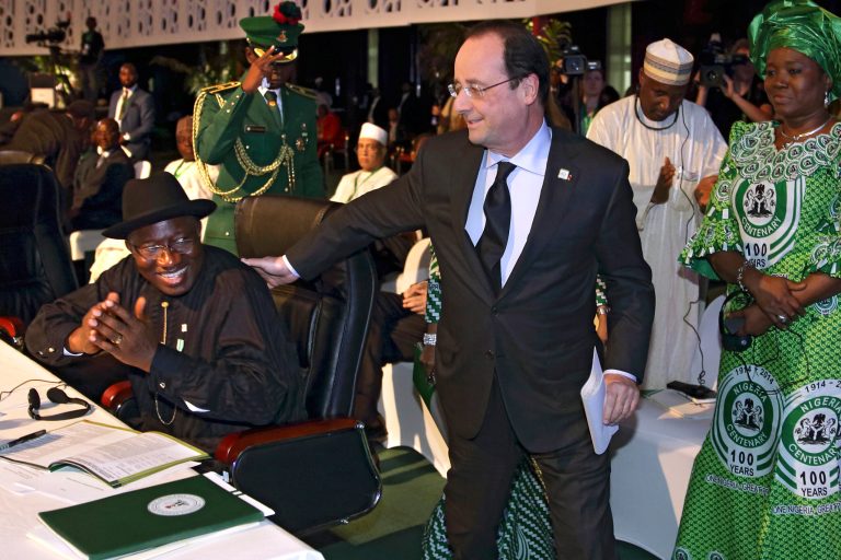 French President Francois Hollande, center, walks past Nigerian President Goodluck Jonathan to deliver a speech during the International Conference on Peace and Security in Abuja, Nigeria, as part of its Centenary celebrations, Thursday, Feb. 27, 2014. Hollande is in Nigeria for a one-day official visit. (AP Photo/Philippe Wojazer, Pool)