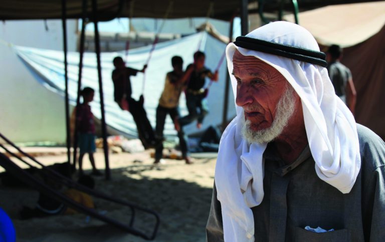 A Syrian refugee passes by the playground at the Jordanian-run Al Bashabsheh refugee camp in Ramtha, Jordan,Tuesday, July 17, 2012. After a visit to the camp Tuesday, the British Foreign Secretary William Hague, not shown, said implementing U.N. special envoy Kofi Annan's peace plan is the 