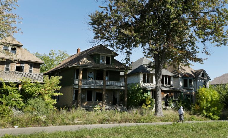 FILE _ In this Sept. 26, 2013 file photo a young man walks in front of a row of abandoned houses in Detroit. Detroit has thousands of decrepit and abandoned homes and buildings. In the little more than a year since emergency manager Kevyn Orr made Detroit the largest U.S. city to seek bankruptcy protection, it has experienced a wide range of improvements that will factor into Judge Steven Rhodes' decisions during next month's bankruptcy trial. That includes a greatly accelerated program to salvage homes that can be rehabilitated and level and clear those that cannot be saved.  (AP Photo/Carlos Osorio, File)