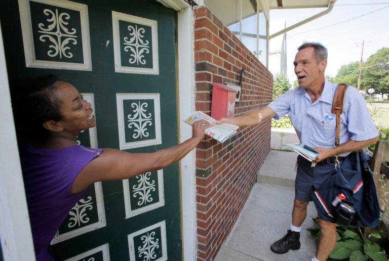 Ohio letter carrier Keith McVey hands the day's mail to Raina Washington as he makes his daily deliveries in Akron, Ohio on Friday, July 16, 2010. (AP Photo)Â 