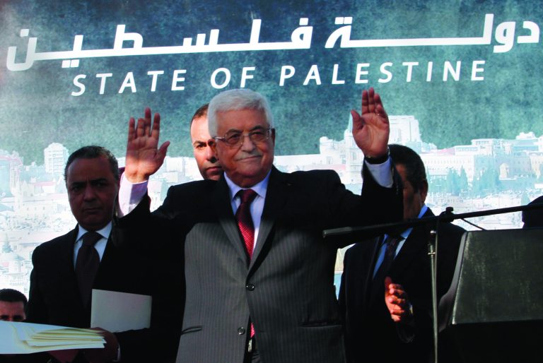 FILE - In this Dec. 2, 2012 file photo, Palestinian President Mahmoud Abbas waves to the crowd during celebrations for their successful bid to win U.N. statehood recognition. Palestinian officials said Monday Jan. 7, 2013, they will not rush to issue new passports and ID cards with the emblem 