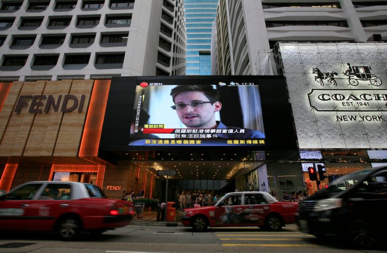 FILE - A large television screen shows a news report on Edward Snowden, a former U.S. National Security Agency contractor who leaked top-secret documents about sweeping U.S. surveillance programs, outside a shopping mall in Hong Kong on Sunday, June 23, 2013. 