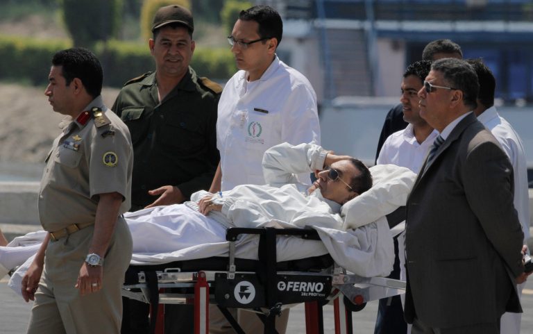 Egyptian medics and army personnel escort former Egyptian President Hosni Mubarak from a helicopter ambulance after it landed at Maadi Military Hospital following a hearing in his retrial in Cairo, Egypt, Saturday, April 13, 2013. Egypt's highest court in January ordered a retrial for Mubarak, for failing to stop the killing of 900 protestors in the 2011 unrest that ousted him, after accepting an appeal against his life sentence, citing procedural failings. (AP Photo/ Amr Nabil)