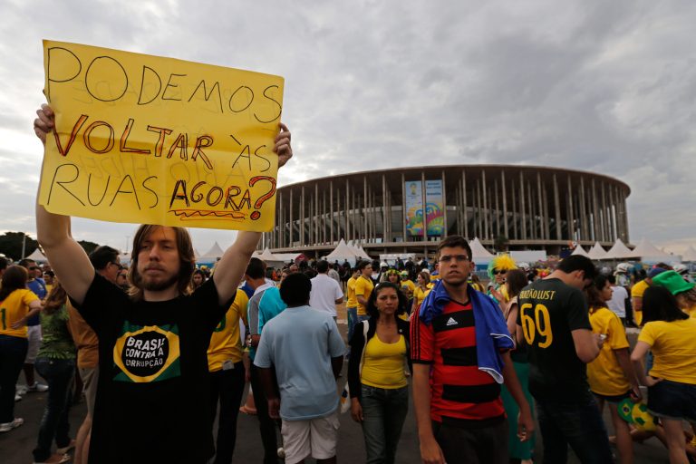 A demonstrator shows poster written in Portuguese that reads, 