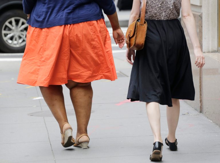 An obese woman, left, walks in New York, Monday, July 13, 2015. (AP Photo/Mark Lennihan)