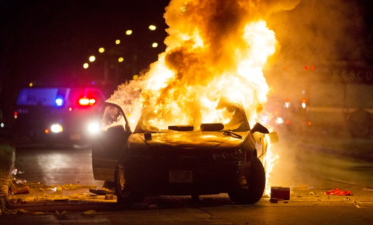 A car burns as a crowd gathers following the fatal shooting of a man in Milwaukee, Saturday, Aug. 13, 2016. (Calvin Mattheis/Milwaukee Journal-Sentinel via AP)