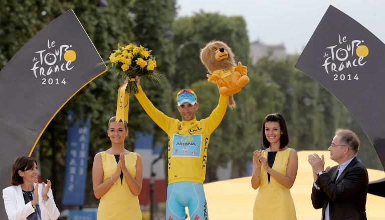 2014 Tour de France cycling race winner Italy's Vincenzo Nibali, wearing the overall leader's yellow jersey, celebrates on the podium in Paris, France, Sunday, July 27, 2014. Left is Paris mayor Anne Hidalgo. (AP Photo/Christophe Ena)