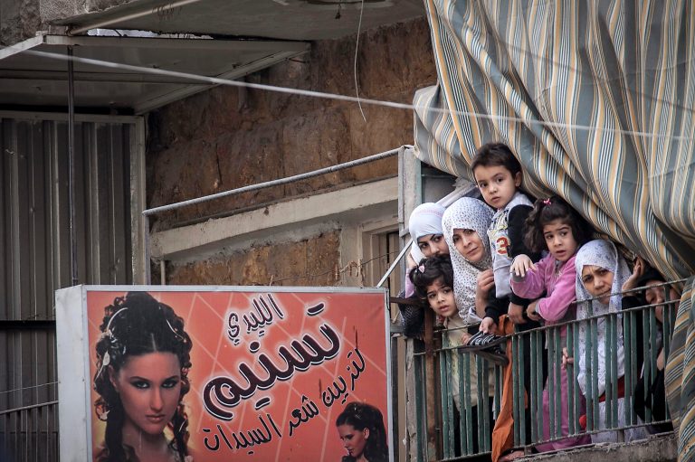   In this Friday, Nov. 30, 2012 photo, Syrian women and children watch a demonstration after Friday prayers in the Bustan Al-Qasr district of Aleppo, Syria. After months of fighting, thousands of residents have returned to the city as they attempt to return to their daily lives while heavy fighting is still taking place along the front lines in the city. Public demonstrations have unfolded after several weeks of silence as residents demand an end to the violence in Aleppo. (AP Photo/Narciso Contreras)  