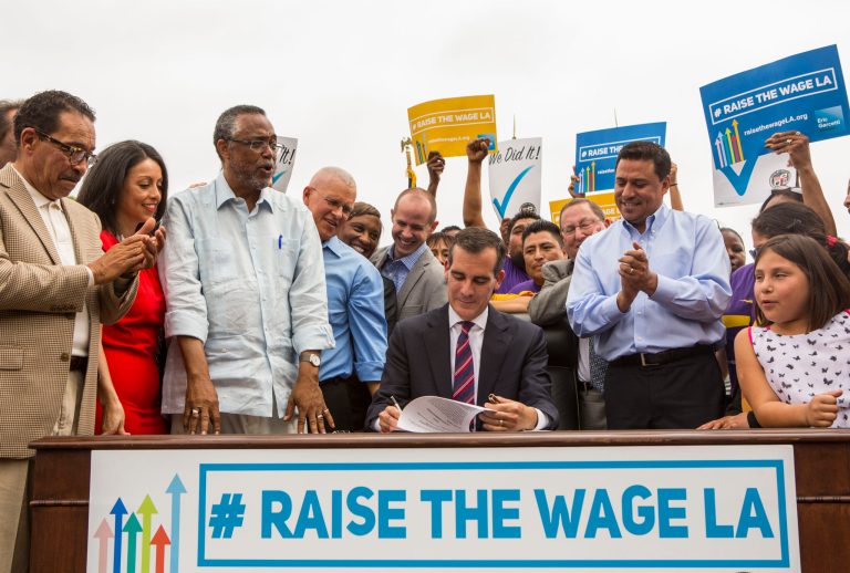 Los Angeles Mayor Eric Garcetti, center, joins members of the City Council and community leaders as he signs into law an ordinance that will gradually raise the minimum wage to $15 an hour by 2020, in Los Angeles, Saturday, June 13, 2015. The ordinance makes Los Angeles the largest city in the U.S. to gradually raise the minimum wage to $15 an hour. (AP Photo/Ringo H.W. Chiu)