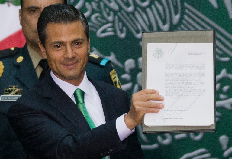 Mexico's President EnriqueÃÂ PeÃ±aÃÂ Nieto holds up the documents he signed to enact his proposed energy reforms at the National Palace in Mexico City on Dec. 20. The sweeping reforms approved by state legislators allow private companies to explore for and produce oil and gas, capping a remarkable series of legislative victories by the Mexican leader. (AP Photo/Eduardo Verdugo)
