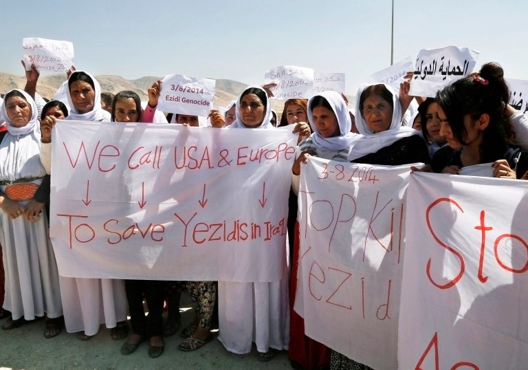 Yazidi Kurdish women hold posters and banners during a protest against the Islamic State group's invasion on Sinjar city one year ago, in Dohuk, northern Iraq, Monday, Aug. 3, 2015. (AP Photo/Seivan M.Salim)