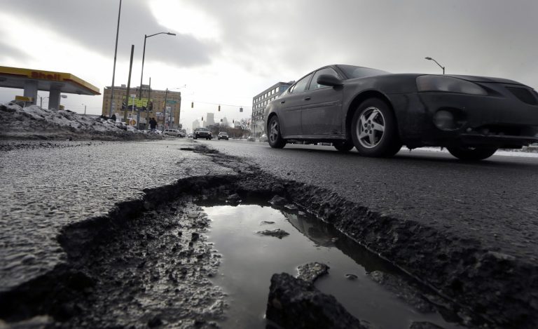 A car drives by a pothole in Detroit. The state House's vote to slowly raise gasoline taxes over time if prices increase has senators asking: Is it enough to fix Michigan's deteriorating roads? Talks are underway on whether lawmakers can capitalize on voter anger over shoddy roads and commit to a much higher tax increase, phased in over a handful of years. (AP Photo/Carlos Osorio, File)