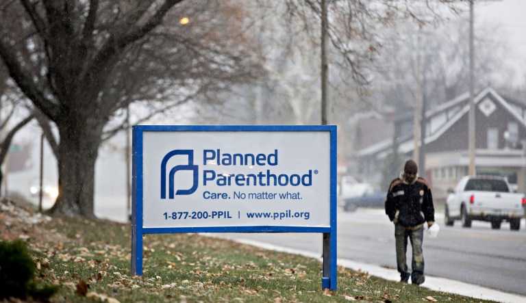 A pedestrian next to signage outside a Planned Parenthood office. 