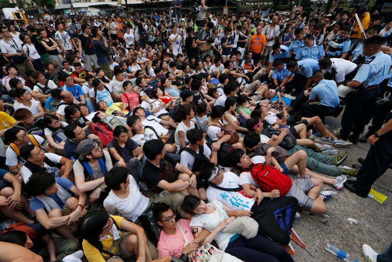 In this July 2, 2014 photo, protesters are taken away by police officers after hundreds of protesters staged a peaceful sit-ins overnight on a street in the financial district in Hong Kong. Hong Kongâs simmering summer of discontent gets even hotter on Sunday when Beijing decides on electoral reforms for the Chinese-controlled financial hub that are likely to step up chances of a showdown with democracy groups. (AP Photo/Kin Cheung)