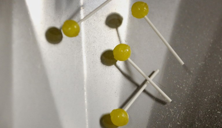 Yellow lollipops spill out of a cooling machine during production in Ohio.