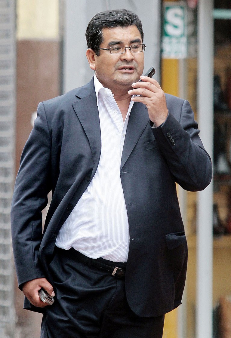 FILE - In this Nov. 26, 2013, file photo, photo, Ancash Gov. Cesar Alvarez talks on his cell phone in Lima, Peru. A Peruvian judge ordered the arrest of Alvarez, Thursday May 15, 2014, on murder charges in the March gangland-style slaying of a political rival who had accused him of running a corrupt, violent mini-dictatorship in a rich mining state. (AP Photo/Edwin Julca, File)