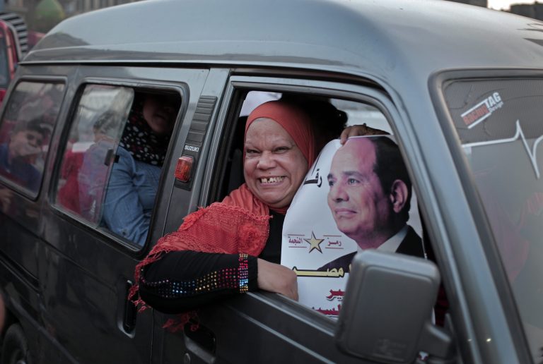 FILE - In this file photo taken Friday, May 16, 2014, an Egyptian supporter of presidential candidate Abdel-Fattah el-Sissi, the country's former military chief, holds a poster of him in downtown Cairo, Egypt. Only a slight majority of Egyptians look favorably on Abdel-Fattah el-Sissi, the former army chief who ousted the elected president and is now a heavy favorite to win next week's presidential elections, according to a poll released Thursday, May 22, by a U.S.-based research center. (AP Photo/Khalil Hamra, File)