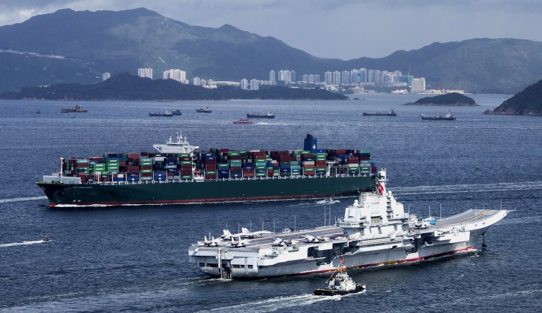 The People's Liberation Army (PLA) Liaoning aircraft carrier, bottom, sails past a container ship in Hong Kong, China.