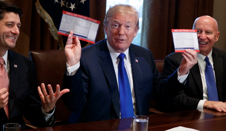 President Donald Trump holds an example of what a new tax form may look like during a meeting on tax policy with Republican lawmakers including House Speaker Paul Ryan of Wis., and Chairman of the House Ways and Means Committee Rep. Kevin Brady, R-Texas, right, in the Cabinet Room of the White House, Thursday, Nov. 2, 2017, in Washington. (AP Photo/Evan Vucci)