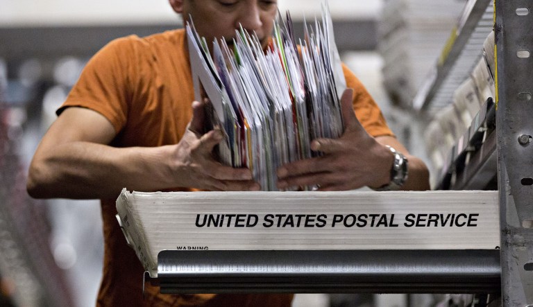 A worker sorts mail into trays at the United States Postal Service (USPS) Suburban processing and distribution center in Gaithersburg, Maryland, U.S., on Tuesday, Dec. 19, 2017.