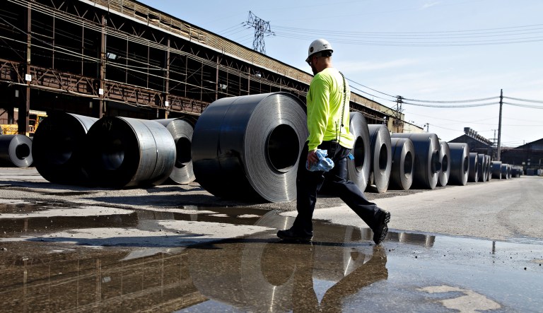 A worker walks past steel coils at the U.S. Steel Corp. Granite City Works facility in Granite City, Ill., Thursday, July 26, 2018.
