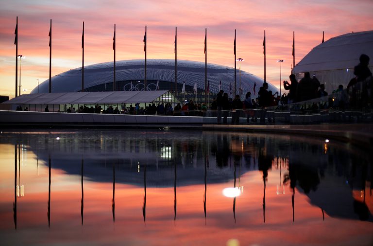 The sun sets as the Bolshoy Ice Dome is reflected in a pool of water underneath the Olympic cauldron at the 2014 Winter Olympics, Thursday, Feb. 13, 2014, in Sochi, Russia. (AP Photo/David Goldman)