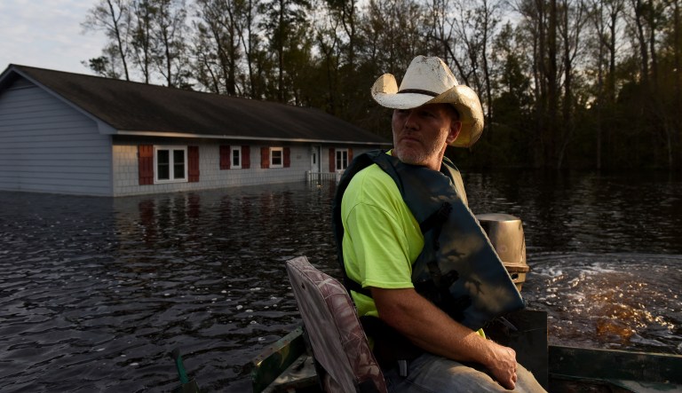 A volunteer navigates a boat on a flooded street to deliver groceries to residents surrounded by water after Hurricane Florence hit in Bergaw, North Carolina, U.S., on Thursday, Sept. 20, 2018.