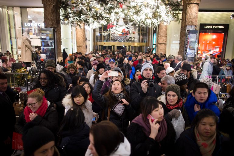FILE - In this Thursday, Nov. 28, 2013, photo, a shopper takes a selfie as crowds pour into the Macy's Herald Square flagship store in New York. The government reports on sales at U.S. retailers in November on Thursday, Dec. 12, 2013. (AP Photo/John Minchillo)