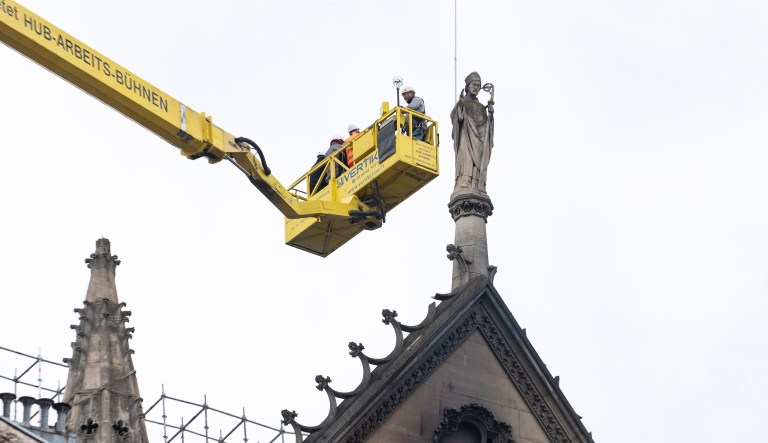 Workers stand in an elevated cherry picker as they inspect the fire-damaged facade of Notre Dame Cathedral in Paris, France, on Tuesday, April 16, 2019.
