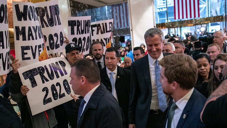 Protesters hold signs while Bill de Blasio, mayor of New York City.