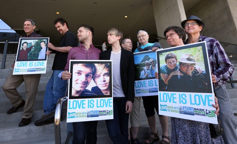 Supporters of same-sex marriage hold photos of themselves and their family members or partners on the steps of the Wayne L Morse U.S. Courthouse Wednesday, May 14, 2014, in Eugene, Ore. (AP Photo/The Register-Guard, Chris Pietsch)