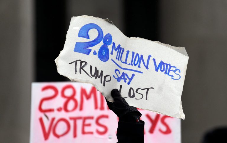 Protesters hold signs outside the Capitol before Electoral College electors begin voting, Monday, Dec. 19, 2016, in Olympia, Wash. Members of Washington state's Electoral College meet at noon Monday in the Capitol to complete the constitutional formality. (AP Photo/Elaine Thompson)