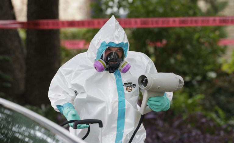 A hazmat worker cleans outside the apartment building of a hospital worker Sunday in Dallas. (AP/LM Otero)