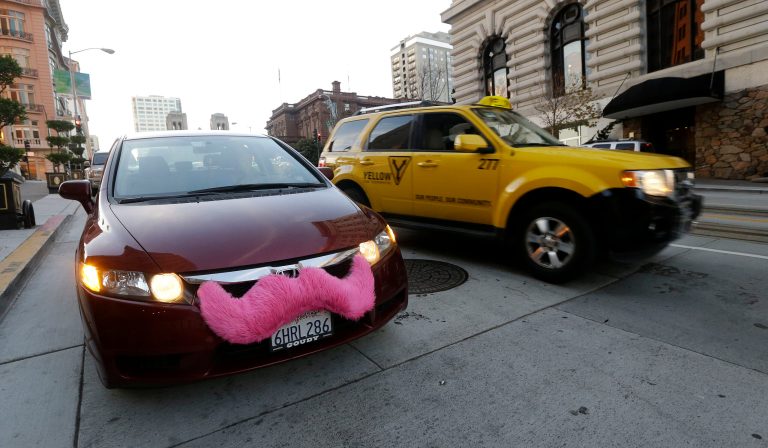 In this Jan. 4, 2013 photo, Lyft driver Nancy Tcheou waits in her car after dropping off a passenger as a taxi cab passes her in San Francisco. (AP File)