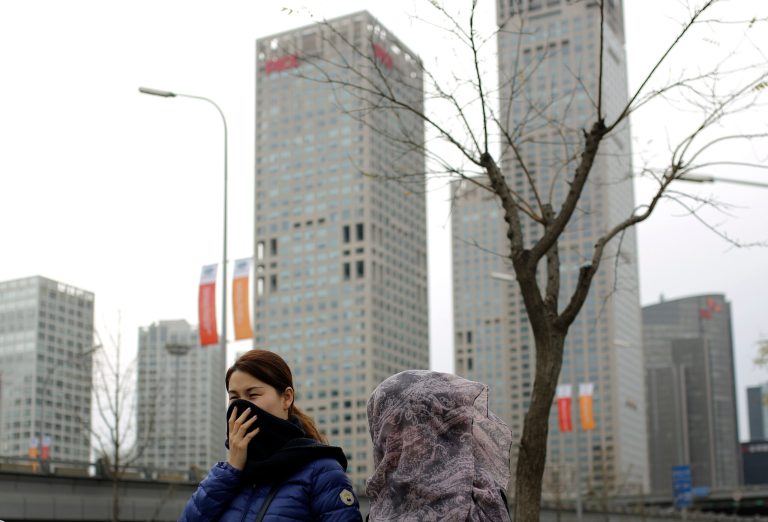 Chinese women cover their face with scarf as they walk past the central business district in Beijing on Tuesday, Nov. 11, 2014. (AP Photo/Andy Wong)