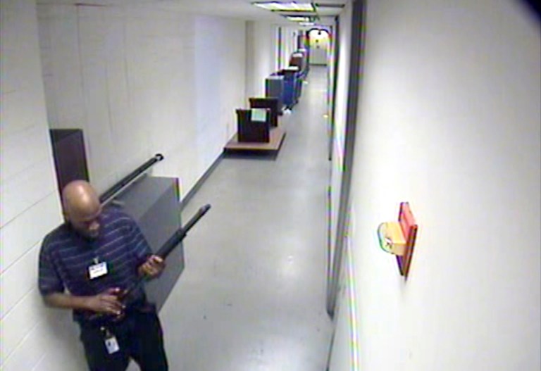 This image from video provided by the FBI, shows Aaron Alexis moving through a hallway of Building #197 at the Washington Navy Yard  in Washington, carrying a Remington 870 shotgun. Senior U.S. officials say the company that employed the Washington Navy Yard shooter withdrew his access to classified material for two days in August when mental health problems became evident, but restored it quickly and never told the Navy about the incident.   (AP Photo/FBI)