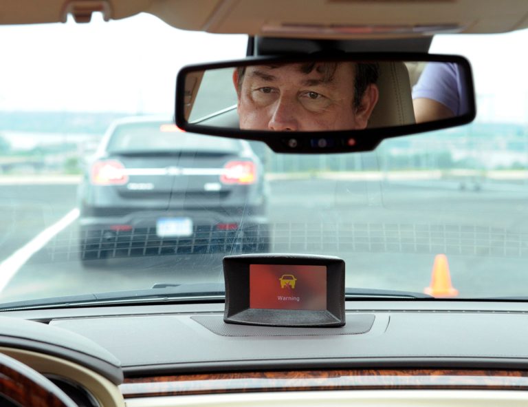 FILE - In this May 22, 2012, file photo,professional test driver Dave McMillan demonstrates the dashboard warning signal in a Buick Lacrosse at an automobile test area in Oxon Hill. The government is speeding up research on safety systems that automatically prevent drivers from operating their cars if they are drunk or aren't buckled properly. Officials also said on Nov. 14, 2013, that they expect to decide by year's end how to encourage automakers to make available in more cars some special safety systems already in certain high-end vehicles. Those systems warn drivers before a collision that they are about to run into another vehicle, and can brake automatically to avoid a crash or make it less severe. (AP Photo/Susan Walsh, File)