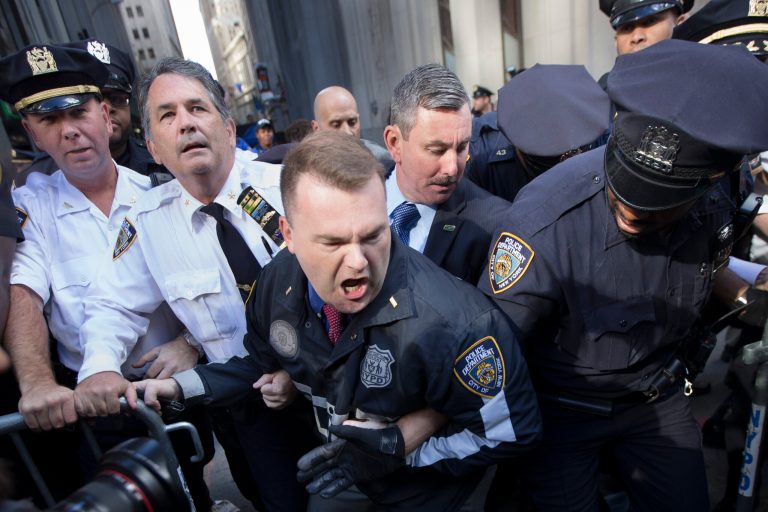 Police officers attempt to secure a barricade blocking protestors from Wall Street during a march demanding action on climate change and corporate greed, Monday, Sept. 22, 2014, a day after a huge climate march in New York. (AP Photo/John Minchillo)