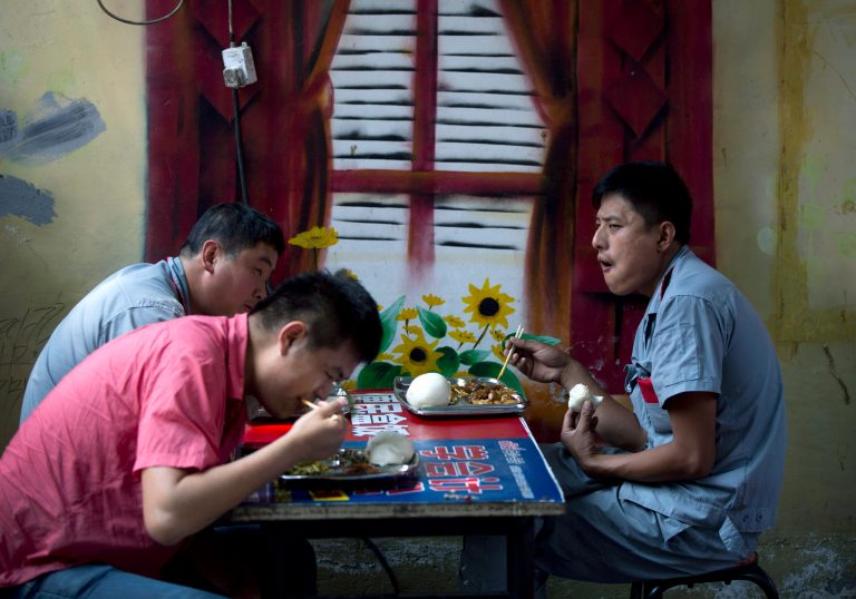 Chinese people eat their lunch next to a wall painted with a window and flowers in Beijing, China Tuesday, June 10, 2014. Higher food prices have pushed China's inflation to a five-month high of 2.5 percent. Data released Tuesday showed consumer inflation in May picked up from the previous month's 1.8 percent. The increase was driven by a 4.1 percent rise in food prices. (AP Photo/Andy Wong)