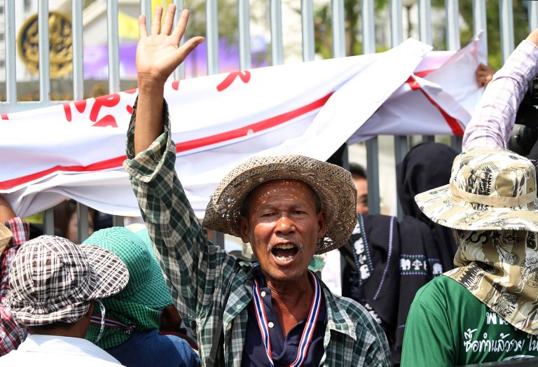 A Thai farmer raises his arm during a rally to demand the government to speed up the payment for the price of their crops outside the Commerce Ministry in Bangkok Thursday, Feb. 6, 2014. An ambitious rice buying program that Thailand's ruling party hoped would uplift millions of its poor rural supporters may end up helping to bring down the increasingly cornered government. (AP Photo/Apichart Weerawong)