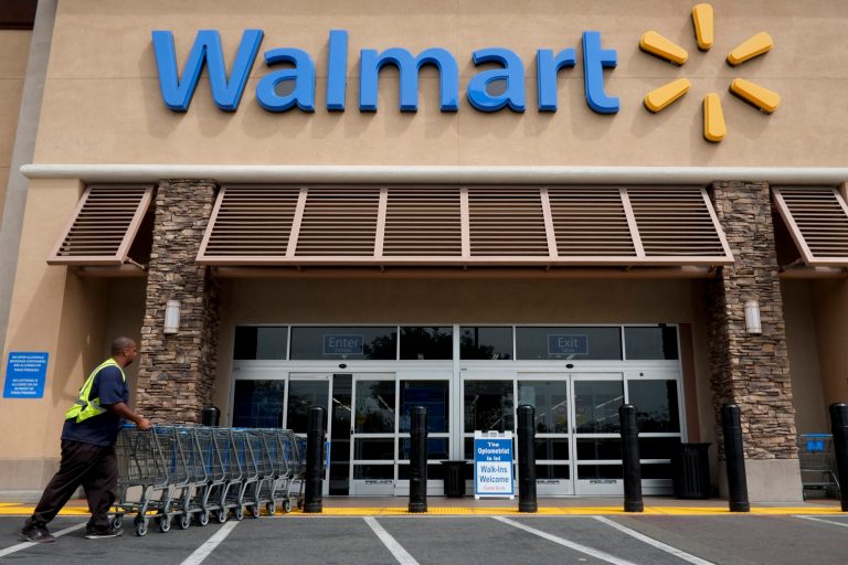 FILE - In this May 9, 2013 file photo, a worker pushes shopping carts in front of a Wal-Mart store in La Habra, Calif. The world's largest retailer plans to work with DirectHealth.com, an online health insurance comparison site and agency, to allow shoppers to compare coverage options and enroll in Medicare plans or the public exchange plans created under the Affordable Care Act. (AP Photo/Jae C. Hong, File)