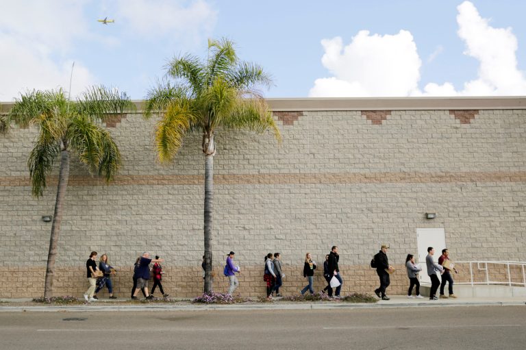 Volunteers carry donated items towards a group of undocumented migrants looking for work as day laborers alongside a hardware store on in San Diego. (AP Photo/Gregory Bull)