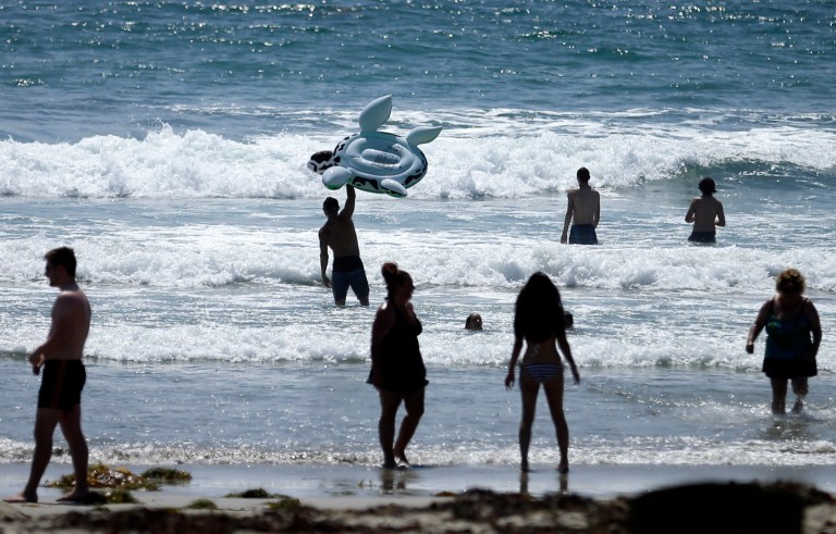 FILE - This, June 24, 2014, file photo shows people swimming on a sunny day at Mission Beach in San Diego. Stop sunbathing and using indoor tanning beds, the acting U.S. surgeon general warned in a report that cites an alarming 200 percent jump in deadly melanoma cases since 1973. (AP Photo/Gregory Bull, File)