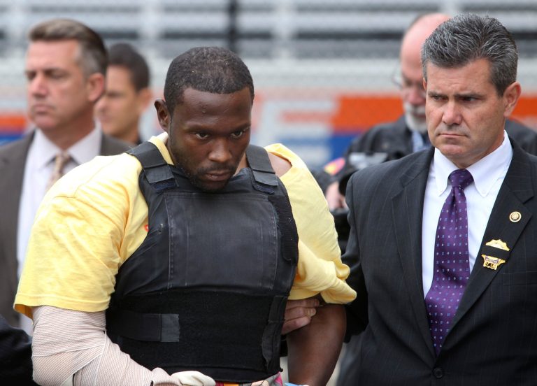 FILE - In this Thursday, Oct. 25, 2012, file photo, Darrell Fuller is escorted out of a police station in Mineola, N.Y. Fuller goes on trial Monday, June 9, 2014, in the killing of a police officer and a second man shot during an alleged carjacking while fleeing the scene of the first shooting. He faces a sentence of life without parole if convicted of the murder charges. (AP Photo/Seth Wenig, File)
