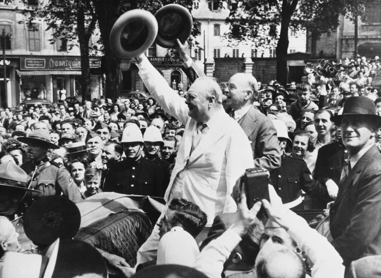 Britain's Prime Minister Winston Churchill, wearing a white suit, and Mackenzie King, Canada's Prime Minister, wave their hats in acknowledgment to a cheering crowd which gathered around their car as they toured Quebec, Canada on Sept. 2, 1943. (AP Photo)