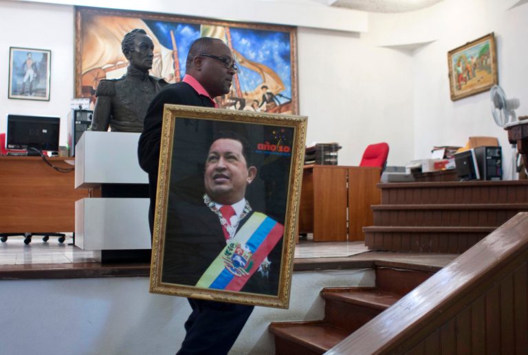   Pierre Denis, who works at Venezuela's embassy, carries an image of Venezuela's President Hugo Chavez after holding a Mass to pray for Chavez's health in Petion-Ville, Haiti, Friday, Dec. 21, 2012. Chavez is recovering in Cuba from surgery, his fourth operation related to pelvic cancer since June 2011. (AP Photo/ Photo/Dieu Nalio Chery)  