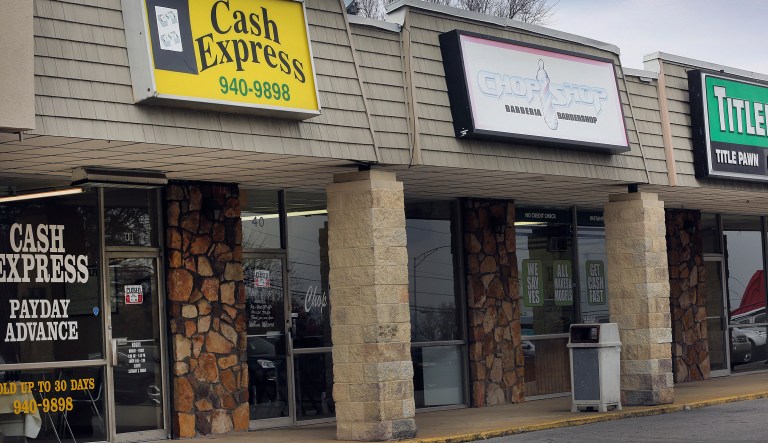 A barber shop stands between two short-term loan stores in Birmingham, Alabama, U.S., on Tuesday, Feb. 10, 2015. In Alabama, the sixth-poorest state, with one of the highest concentrations of lenders, advocates are trying to curb payday and title loans, a confrontation that clergy cast as God versus greed. They have been stymied by an industry that metamorphoses to escape regulation, showers lawmakers with donations, packs hearings with lobbyists and has even fought a common database meant to enforce a $500 limit in loans. Photographer: Gary Tramontina/Bloomberg
