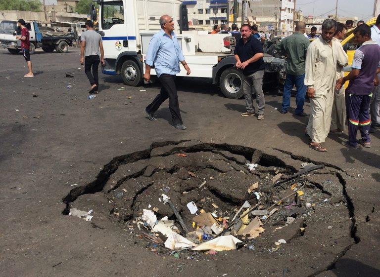 Civilians inspect a crater caused by a car bomb explosion in commercial area of New Baghdad, Iraq, Tuesday, Aug. 26, 2014. The parked car bomb exploded on Tuesday in a busy area in eastern Baghdad, killing and wounding scores of people, officials said, the latest in a series of attacks to shake the Iraqi capital as the Shiite-led government struggles to dislodge Sunni militants from areas in the country's west and north. (AP Photo/ Khalid Mohammed)